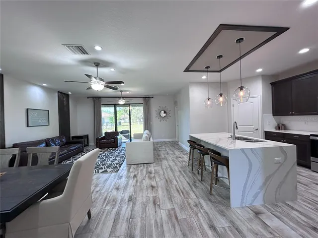 a large kitchen with stainless steel appliances a stove a sink dishwasher a dining table and chairs with wooden floor