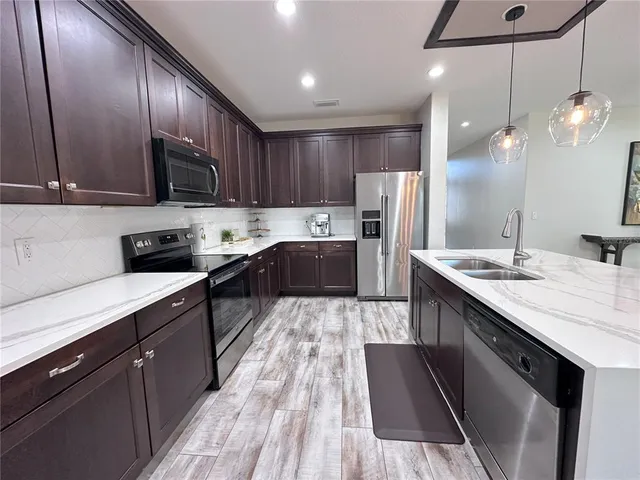 a large kitchen with stainless steel appliances kitchen island granite countertop a sink stove and refrigerator