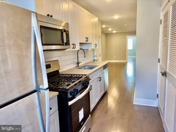 a kitchen with stainless steel appliances granite countertop a sink a stove cabinets and wooden floor