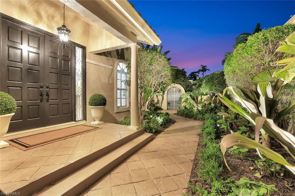 211 Via Napoli Naples, FL 34105 - Photo 3 of 50 a yellow house with a yard and potted plants