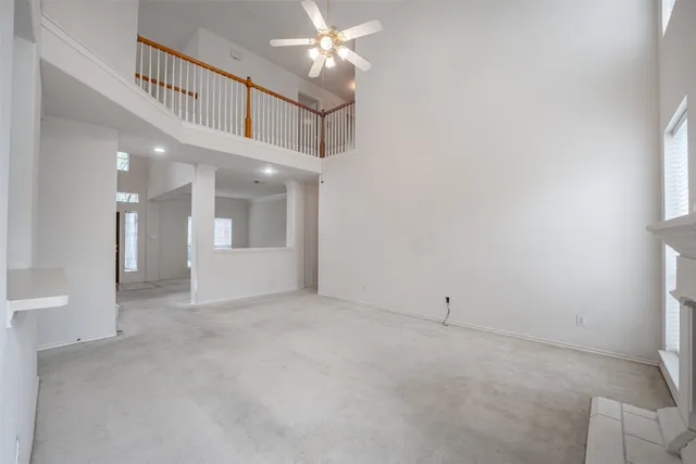 a view of an empty room with chandelier fan