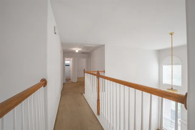 a view of a hallway with wooden floor and a bathroom