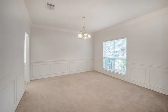 an empty room with windows and chandelier fan