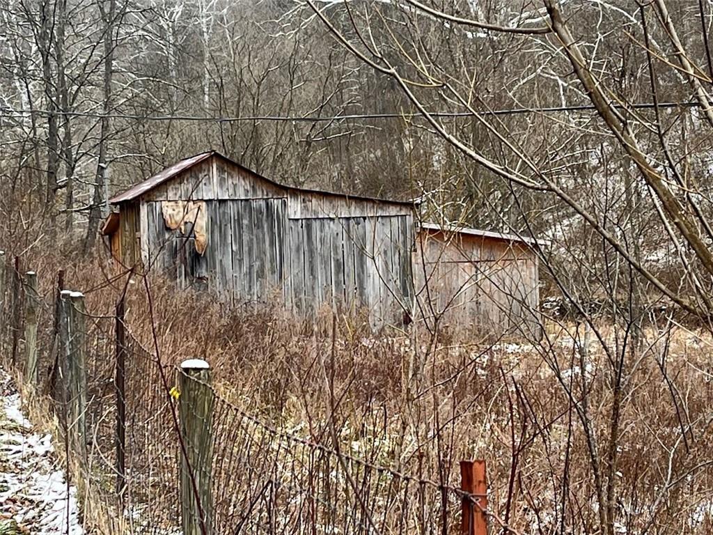 a view of a wooden building with large tree and wooden fence