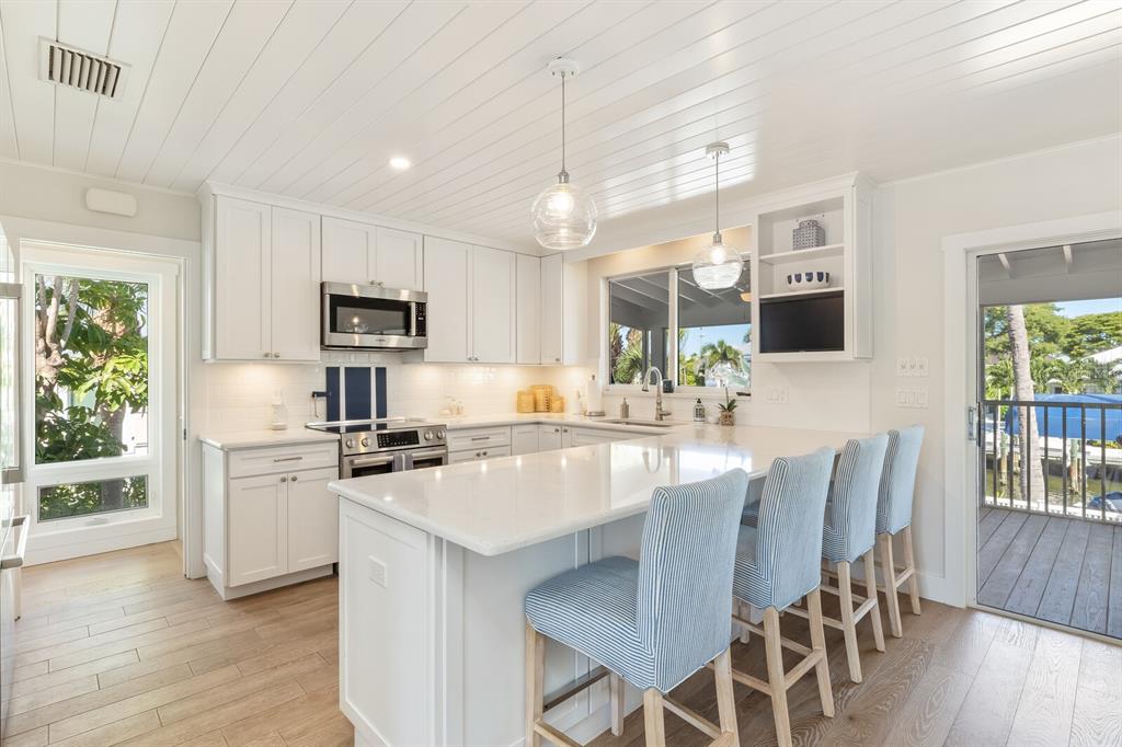 161 1st Street East Boca Grande, FL 33921 - Photo 5 of 38 a large kitchen with kitchen island white cabinets and stainless steel appliances