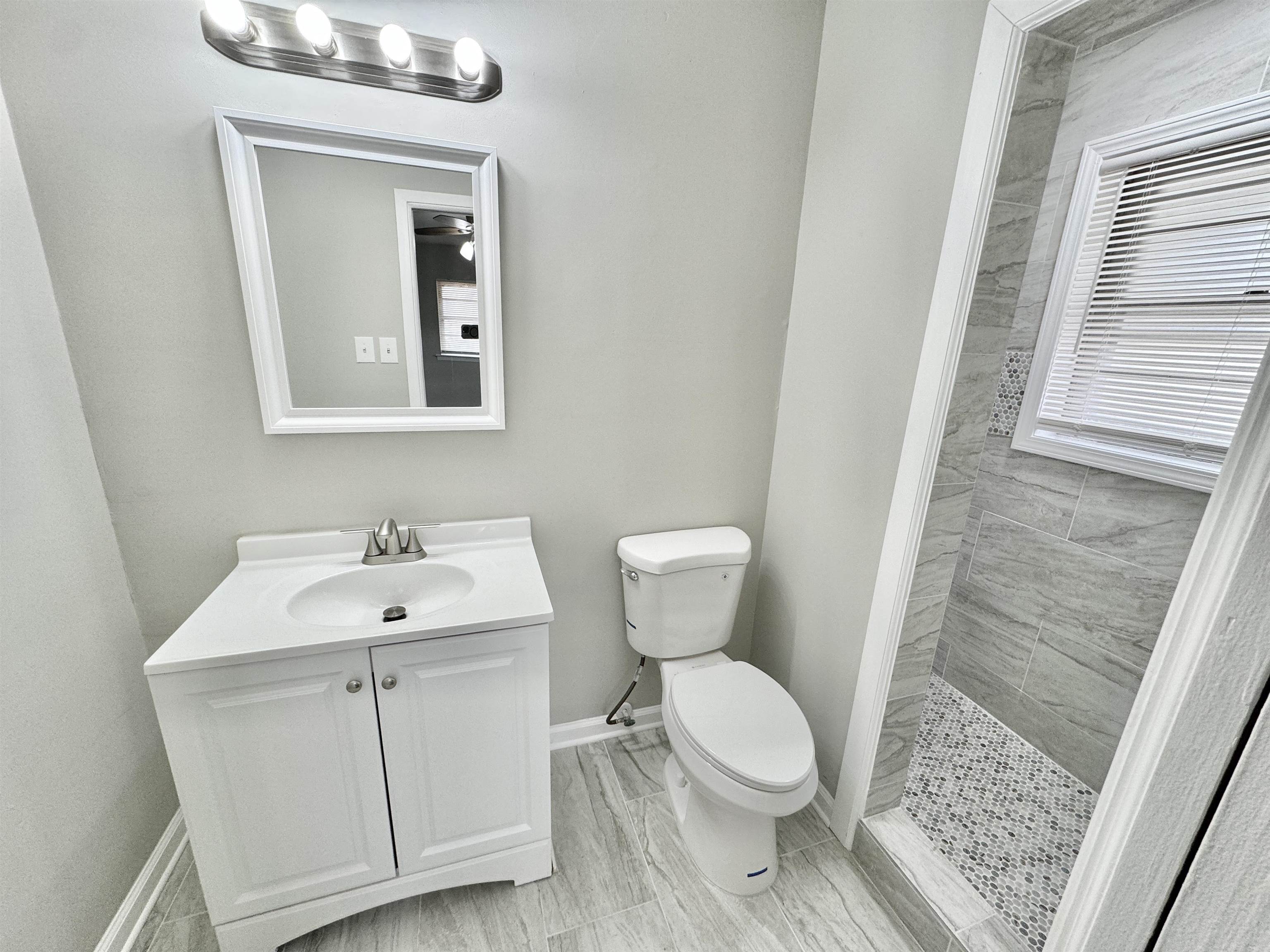 2009 West Holmes Road Memphis, TN 38109 - Photo 13 of 28 Bathroom featuring toilet, tiled shower, vanity, and baseboards