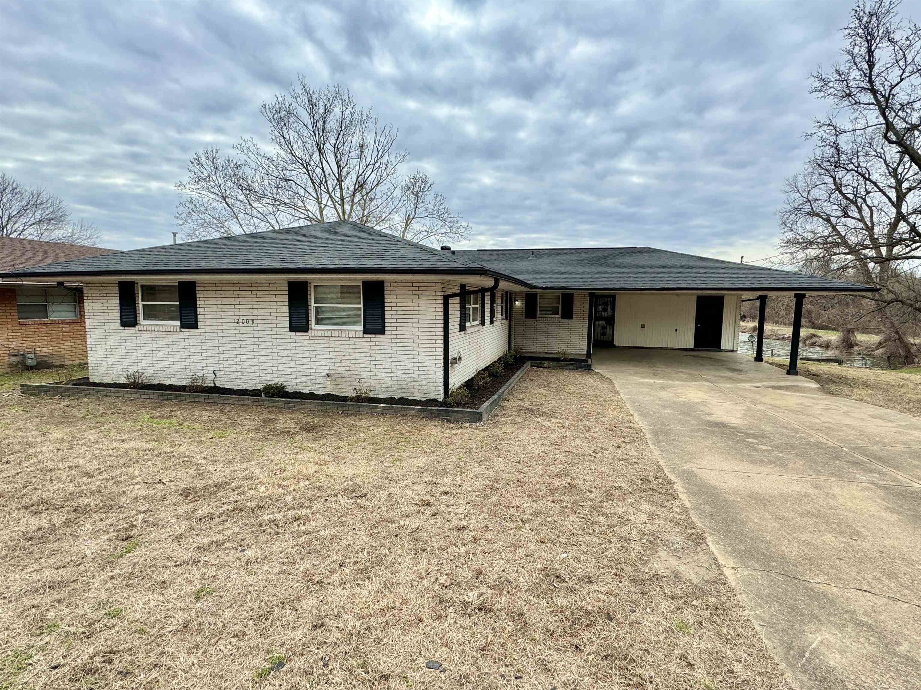 2009 West Holmes Road Memphis, TN 38109 - Photo 28 of 28 Ranch-style house featuring brick siding, concrete driveway, roof with shingles, a carport, and a front yard