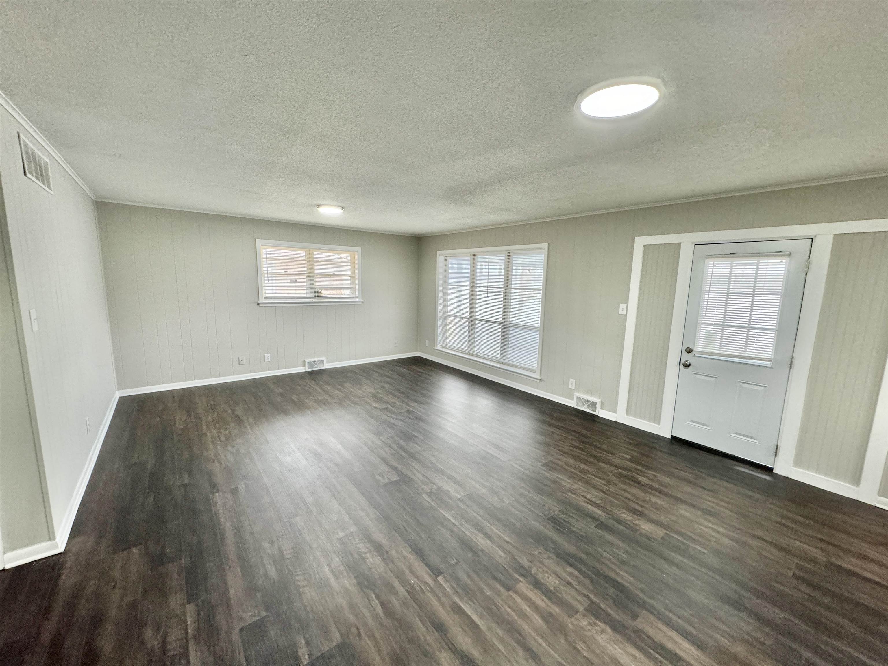 Interior space with dark wood-style flooring, visible vents, and baseboards