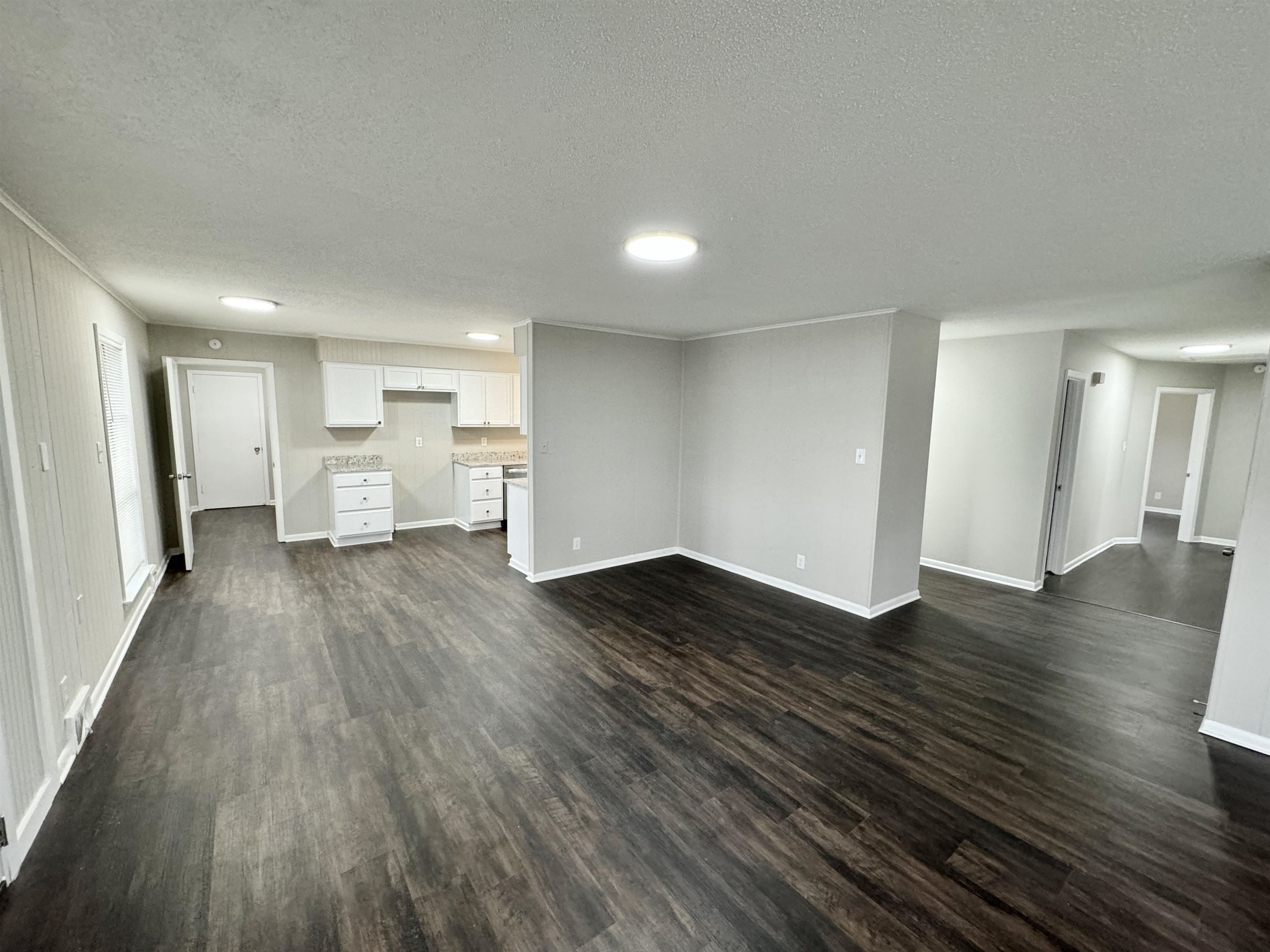 2009 West Holmes Road Memphis, TN 38109 - Photo 8 of 28 Unfurnished living room with a textured ceiling, baseboards, and dark wood-style flooring