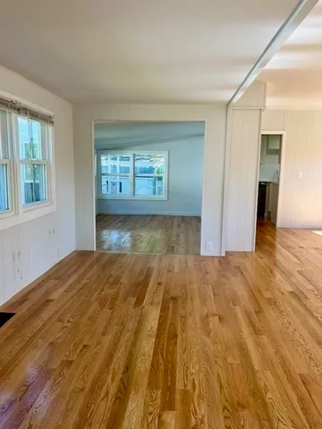a view of an empty room and window and wooden floor