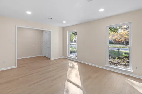 a view of empty room with wooden floor and fan