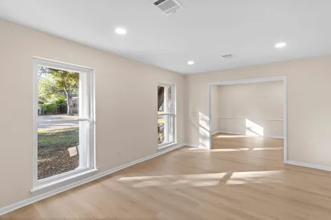 a view of empty room with window and wooden floor