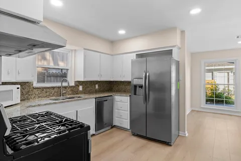 a kitchen with stainless steel appliances granite countertop a stove a refrigerator and a sink