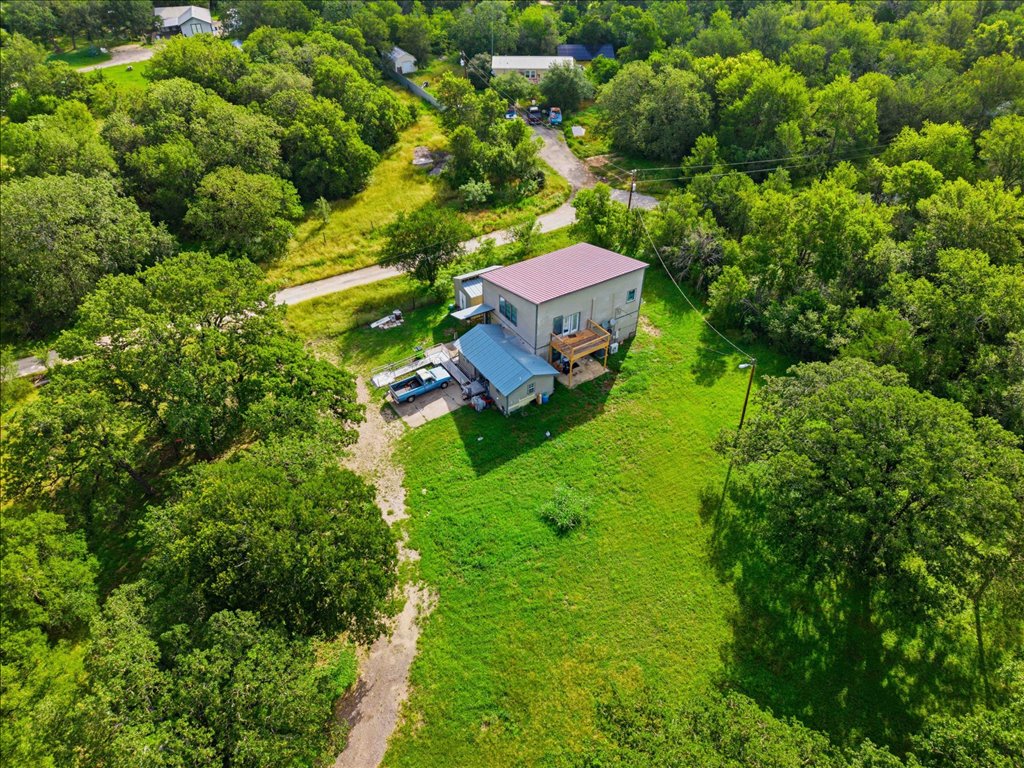 211 Webberwood Way Elgin, TX 78621 - Photo 7 of 10 A secluded dwelling nestled amidst verdant trees and open land, offering a tranquil retreat.