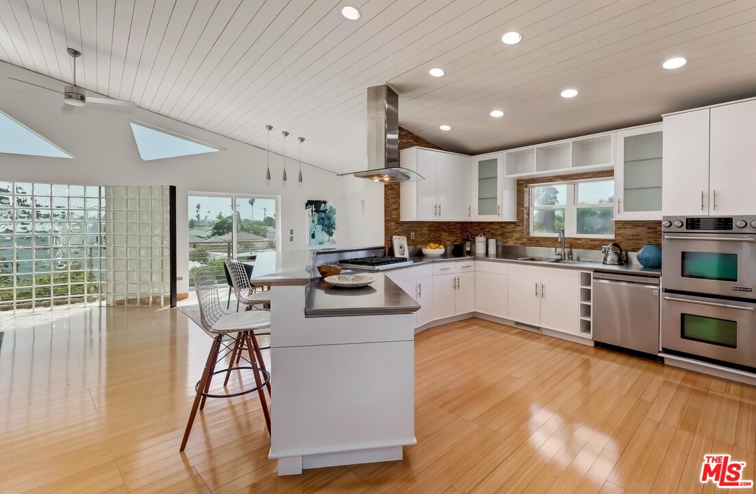 899 Commonwealth Avenue Venice, CA 90291 - Photo 7 of 47 a kitchen with stainless steel appliances kitchen island granite countertop a stove a sink a refrigerator and cabinets