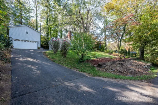a pathway of a house with a yard and a large tree