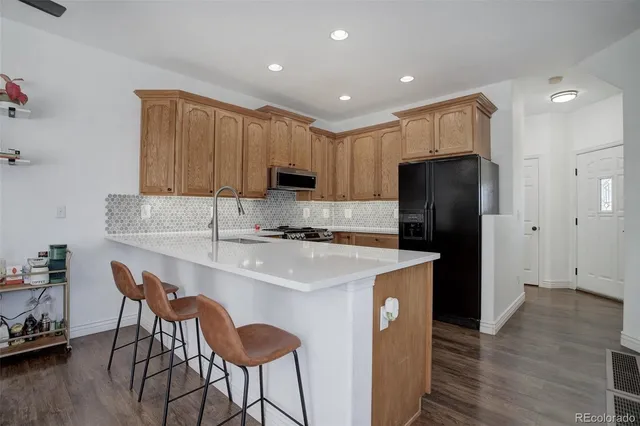 a kitchen with kitchen island a stove a sink and a refrigerator with wooden floor