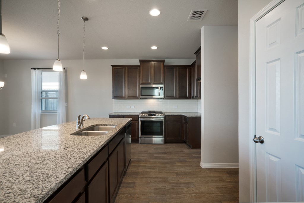 205 Guemal Road Buda, TX 78610 - Photo 10 of 33 a kitchen with stainless steel appliances granite countertop a sink and stove top oven
