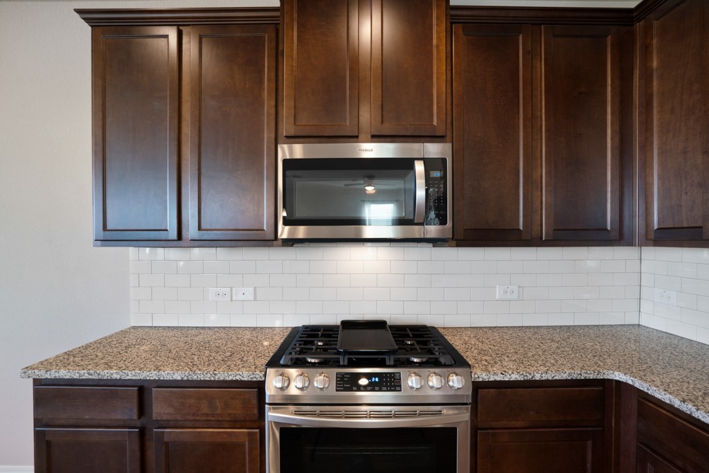 205 Guemal Road Buda, TX 78610 - Photo 11 of 33 a kitchen with granite countertop a stove and a microwave