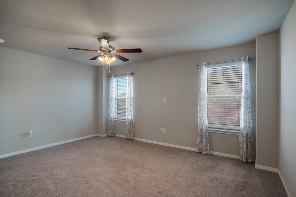 205 Guemal Road Buda, TX 78610 - Photo 15 of 33 a view of an empty room with a ceiling fan and a window