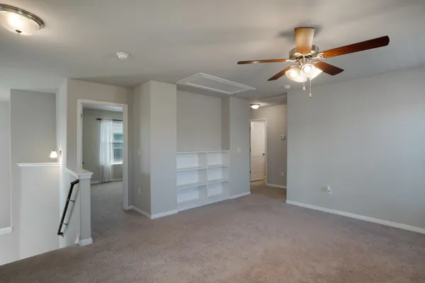 a view of an empty room with a ceiling fan and a window
