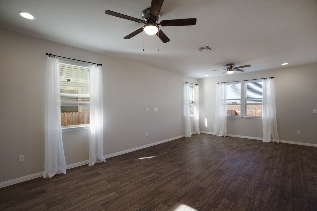 205 Guemal Road Buda, TX 78610 - Photo 6 of 33 a view of an empty room with wooden floor and a window