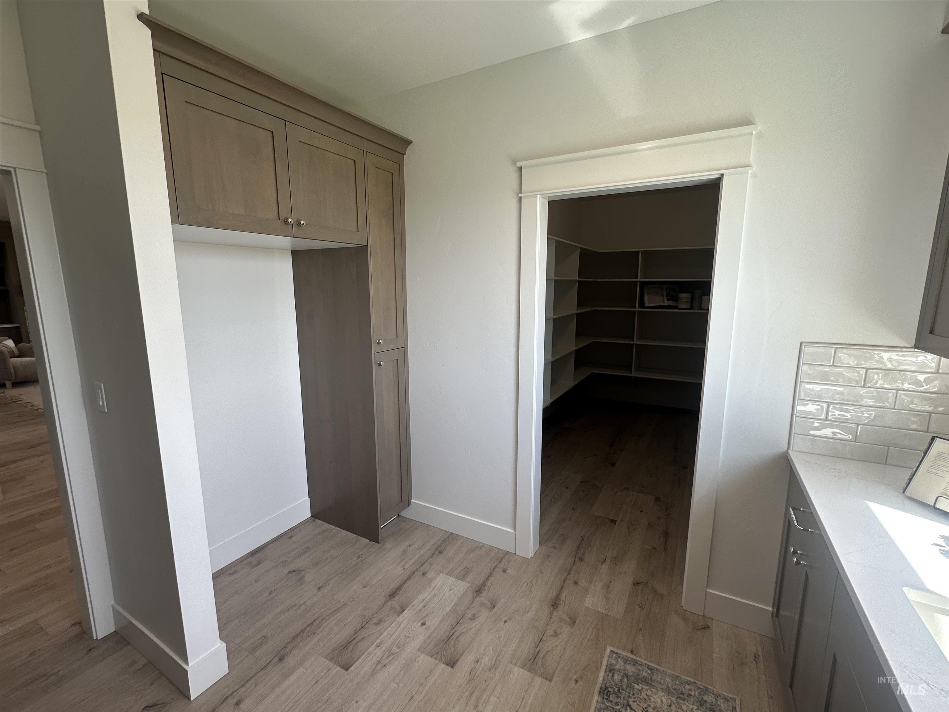 3035 Lake View Twin Falls, ID 83301 - Photo 12 of 41 Kitchen featuring light wood-finish flooring, white subway tile backsplash, white countertops, and dark cabinetry