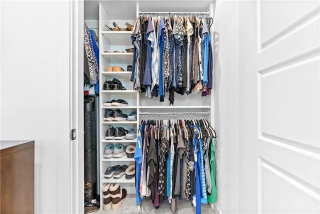 a view of walk in closet with clothes and shoes