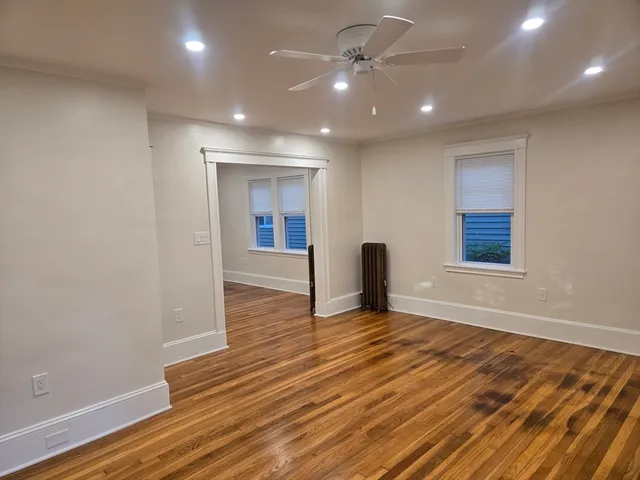 a view of an empty room with wooden floor and a window