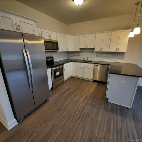 a kitchen with granite countertop a refrigerator stove and wooden cabinets