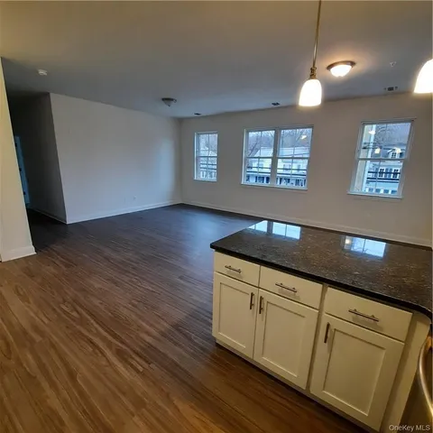 a kitchen with granite countertop a sink cabinets and a wooden floor