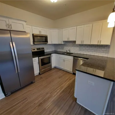 a kitchen with stainless steel appliances granite countertop a refrigerator a sink dishwasher a stove top oven a refrigerator and white cabinets