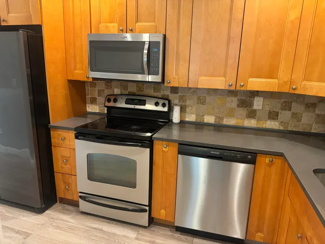 a kitchen with granite countertop cabinets stainless steel appliances and a counter space