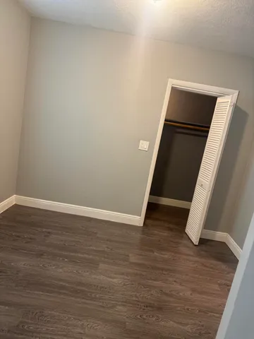 a view of an empty room with wooden floor and closet