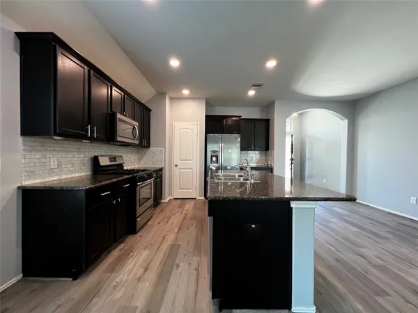 a large kitchen with stainless steel appliances and wooden cabinets