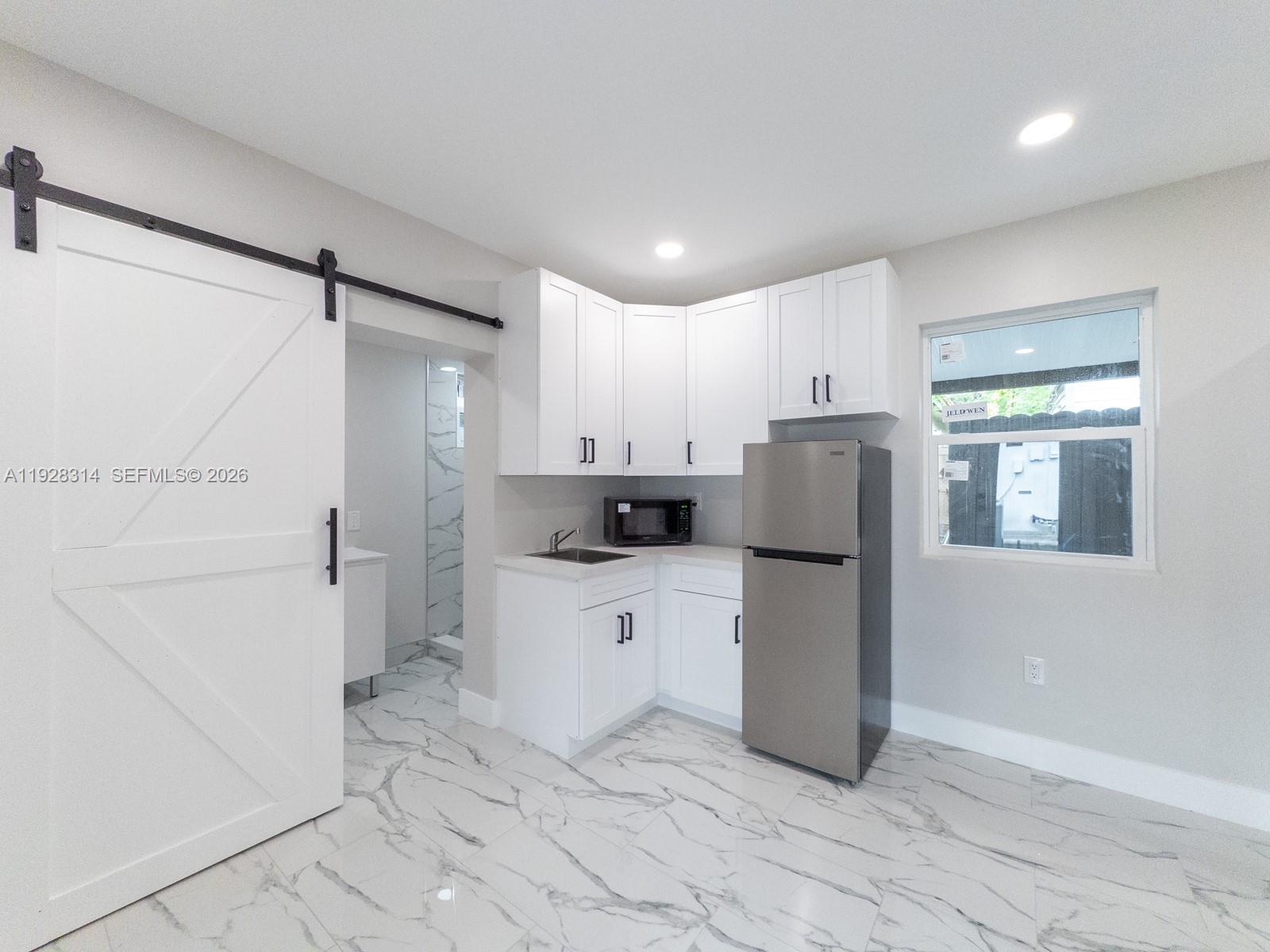 3360 Southwest 24th Terrace, Unit 3362B Miami, FL 33145 - Photo 4 of 15 a kitchen with a refrigerator and white cabinets