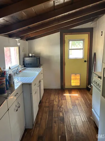 a view of a kitchen with a sink and dishwasher with wooden floor