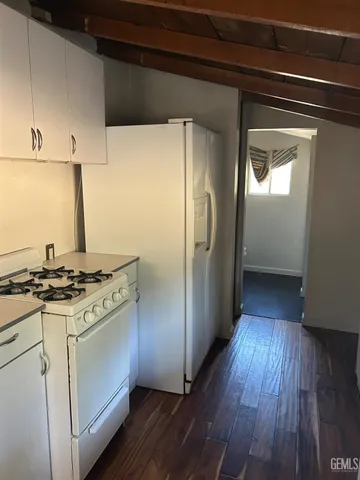 a kitchen with a stove a refrigerator and a wooden floor