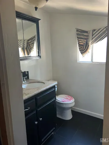 a bathroom with a granite countertop toilet a sink and a window
