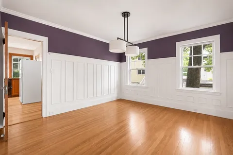a view of empty room with wooden floor chandelier and windows