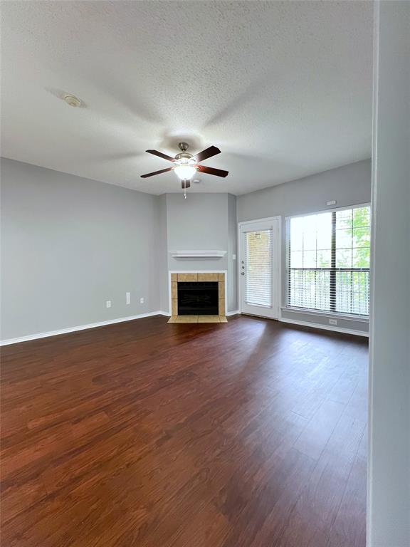 a view of an empty room with wooden floor fireplace and a window