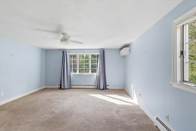 an empty room with chandelier fan and windows