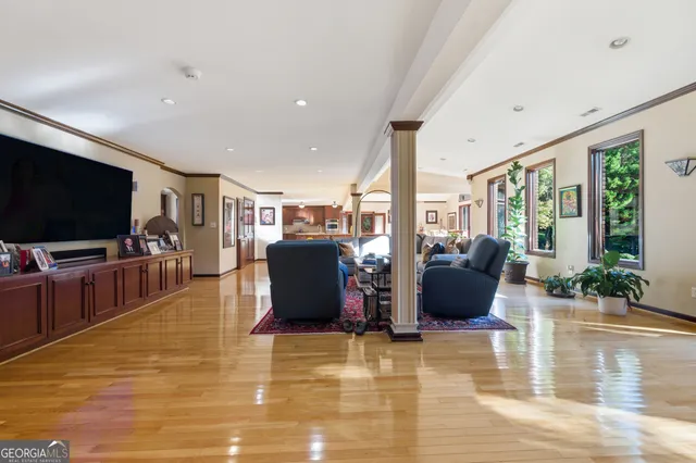 a living room with furniture a flat screen tv and floor to ceiling window