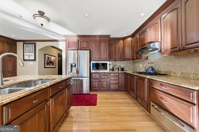 a large kitchen with stainless steel appliances granite countertop a stove refrigerator sink and cabinets