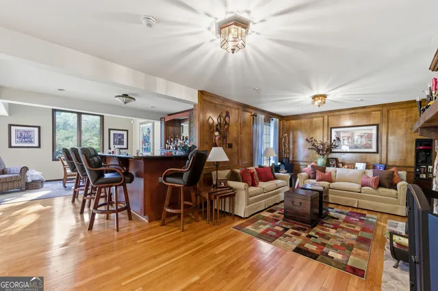 a living room with furniture a dining table and a bookshelf with wooden floor
