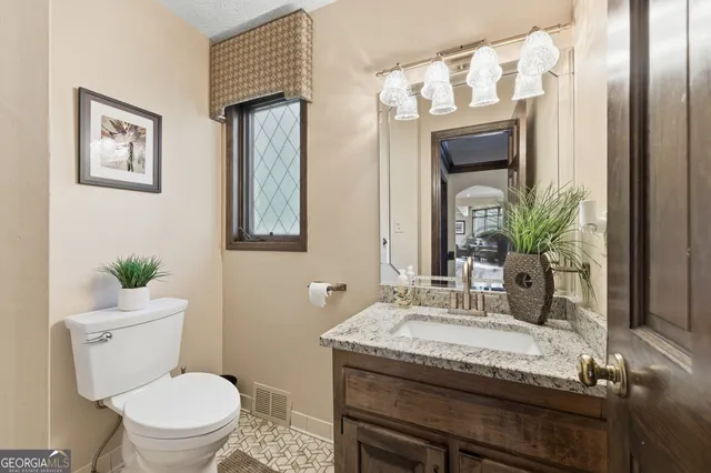 a bathroom with a granite countertop sink a toilet and mirror