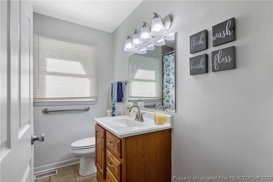 6433 Milford Road Fayetteville, NC 28303 - Photo 37 of 46 a bathroom with a toilet sink and mirror