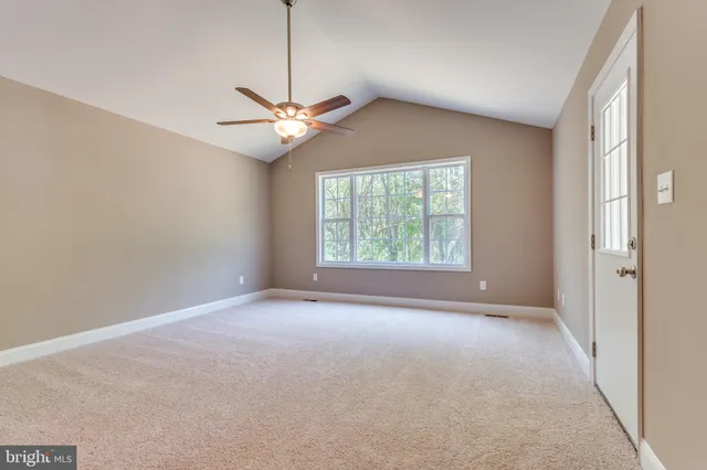 an empty room with a window and a fan