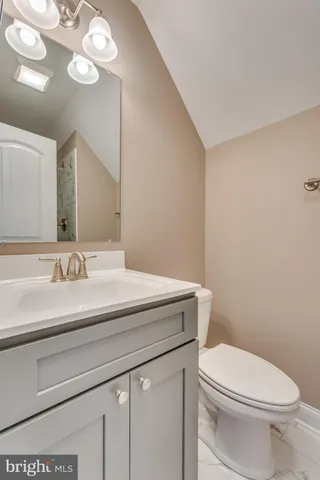 a bathroom with a granite countertop toilet sink and mirror