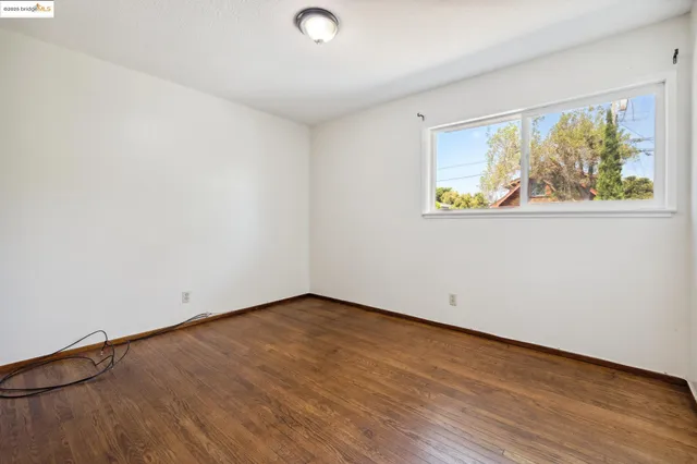 an empty room with wooden floor and window